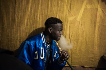 Ousmane is a young boy from Niger but raised in Libya. He has always been passionated about trap music and has managed to get a small space in the basement of the blue building, where he can record and mix his songs. Turin.